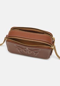 Borsa a tracolla in pelle marrone con catena dorata, doppi scomparti con zip e dettagli ricamati bianchi sulla parte frontale. Finitura testurizzata.