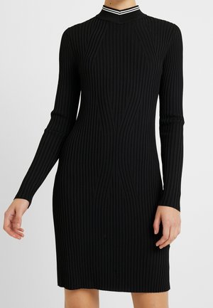 Dopasowana czarna sukienka z prążkowanego dzianiny, z długimi rękawami i wysokim kołnierzem, ozdobiona białym podwójnym paskiem.