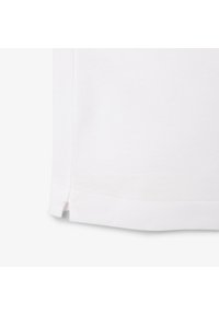 Bílá bavlněná tričko s jemnou texturou. Má rovný lem a boční rozparky pro snadný pohyb. Jednoduchý a klasický design.