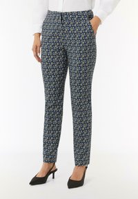 Patronen broek in blauw en beige van geweven stof, slim fit ontwerp, met zakken en een rits bij de enkel. Gecombineerd met zwarte hakken.