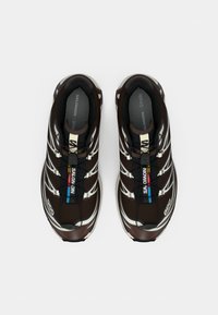 Brūni sporta apavi ar teksturētu virsmu, baltām detaļām un ātru auklu sistēmu. Iekļauj mīkstu iekšzoli komfortam.