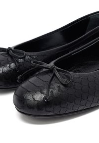 Bailarinas de cuero negro con un patrón texturizado similar a escamas, con puntera redonda y un delicado lazo en la parte delantera.