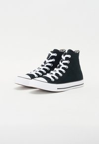 Sorte høye sneakers laget av lerret, med hvite snørebånd, gummitupper og fôr med leopardmønster. Kontrasterende hvit såle med svarte striper.