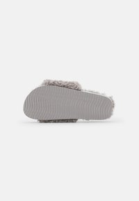 Gray fuzzy slipper with a textured, curved sole. Soft upper material and a slightly raised heel. Hesitant border where upper meets sole.
