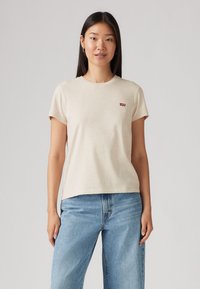 Beige crew-neck t-skjorte i myk bomull, med kort erm og et lite rødt Levi's logo-merke på venstre bryst. Klassisk, avslappet passform.