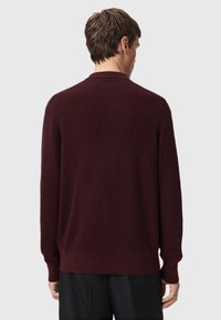 Burgundy sweater with a textured knit, crew neckline, and long sleeves. Ribbed hem and cuffs detail in a relaxed silhouette.