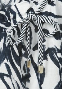 White fabric with black and navy abstract pattern. Features a drawstring tie in twisted black and white cotton, accented with gold metal tips.