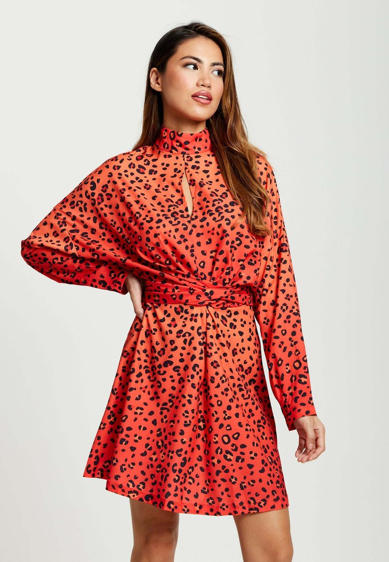 Red leopard-print dress with long sleeves, a high-neck design, and a keyhole detail at the neckline. Smooth, lightweight fabric.