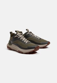 Groene mesh sport schoenen met donkere accenten, rubberen zool en een gestructureerde grip. Voorzien van veters en een trekband aan de achterkant voor eenvoudig aan- en uittrekken.