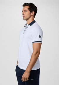 Biele polo tričko s námorníckym golierom a manžetami, s vertikálnym logom na zapínaní a námorníckym akcentom loga na rukáve.