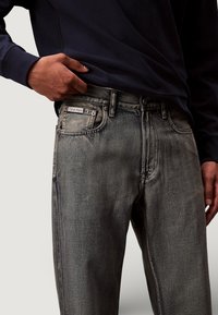 Jeans neri slavati da uomo con taglio dritto, con logo Calvin Klein sulla tasca frontale, cinque tasche e passanti per cintura.