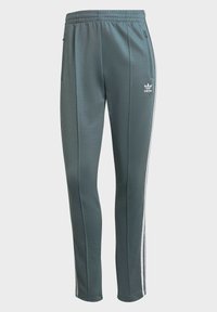 Pantaloni sportivi verde scuro con vestibilità affusolata, vita elastica, tasche laterali e strisce bianche lungo i lati. Logo Adidas davanti.