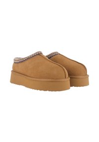 Zapatillas de ante en tono arena, sin cordones, con punta redonda, suela de goma gruesa y costuras decorativas a lo largo del borde. Textura ligera y suave.