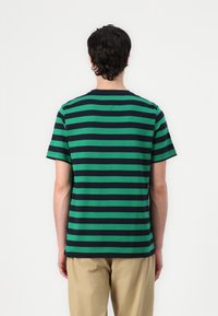T-shirt rayé vert et bleu marine en coton doux, design à col rond, manches courtes et détail de couture sur les côtés au dos.