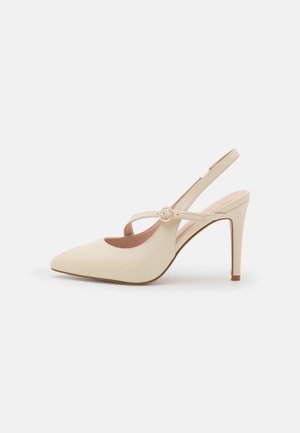 Beżowe szpilki typu slingback z zaostrzonym noskiem, cienkim paskiem i okrągłą sprzączką na podbiciu, na białym tle.