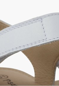 Sandale en cuir blanc avec une texture lisse, présentant des brides larges, une couture discrète et une semelle intérieure de couleur naturelle.