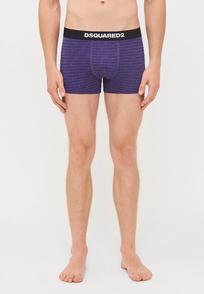 Boxers violets avec une taille noire comportant le texte répété "DSQUARED2". Fabriqués en tissu doux, conçus pour le confort et l'ajustement.