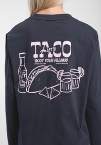 Marineblaue Sweatshirt mit pinkem Grafikdruck eines Tacos, einer Flasche scharfer Sauce, Nachos und Getränken, im lässigen Schnitt und mit geripptem Rundhalsausschnitt.
