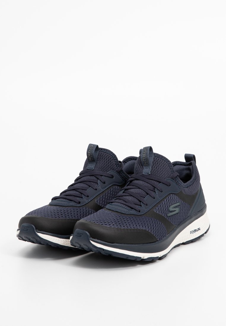 Baskets de sport en maille navy avec un col rembourré, des superpositions en synthétique noir et une semelle blanche avec des accents gris. Design lacé avec un détail de logo.