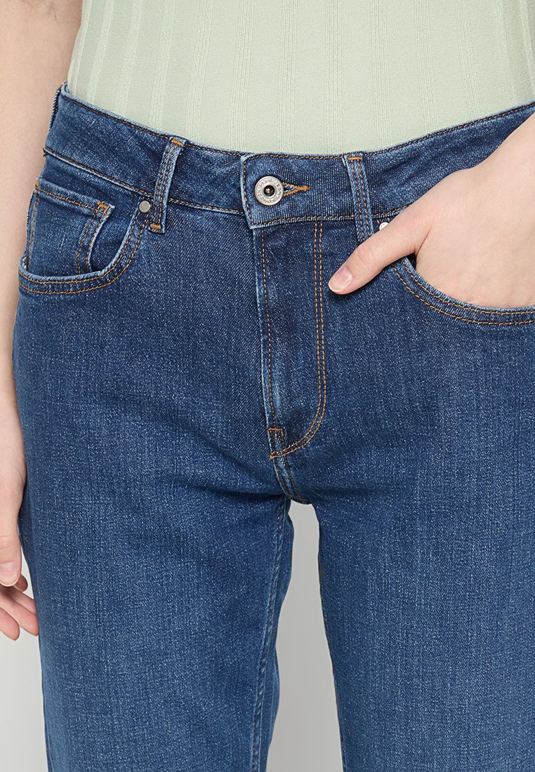 Blaue Jeans aus Denim mit einem klassischen Fünf-Taschen-Design, weißer Naht und einem Metallknopfverschluss am Bund.