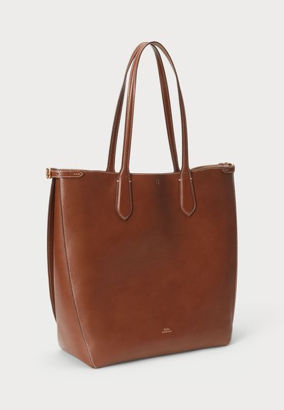 Bruine leren tote bag met twee lange handvatten, een gladde textuur, een minimalistisch ontwerp en subtiele stiksels, voorzien van een ritssluiting.