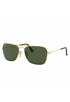 Occhiali da sole aviator in metallo dorato con lenti verde scuro, barra sopracciliare inclinata e punte delle aste nere. Le montature sono sottili e con una forma geometrica.