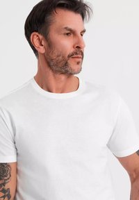 Hvid bomulds T-shirt med rund halsudskæring og korte ærmer, med en glat tekstur og enkelt design. Ingen mønstre eller accenter er synlige.