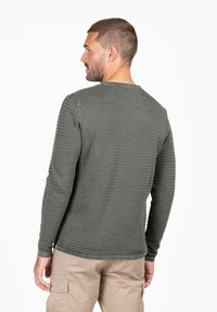Langärmliges Shirt in Olivgrün, mit horizontalen Streifen strukturiert. Besitzt einen Rundhalsausschnitt und taillierte Ärmel. Rückansicht dargestellt.