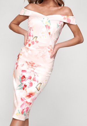 Schulterfreies, knielanges Kleid mit pinkem Blumen- und Schmetterlingsmuster auf hellem Hintergrund, getragen von einer Frau mit Händen in der Hüfte.