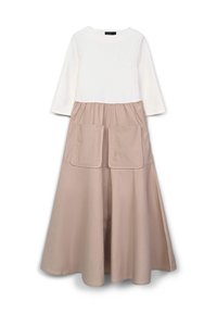 Top bianco a maniche lunghe con scollatura rotonda, abbinato a una gonna beige a trapezio con due grandi tasche frontali. Tessuto morbido.