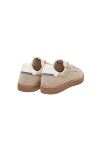 Beige suede sneakers with white leather accents, flat laces, perforations on side, and a brown rubber sole. Rounded shape and casual design.
