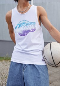 Biała bezrękawnikowa koszulka z kolorową grafiką "Los Angeles Lakers", zestawiona z luźnymi niebieskimi szortami dżinsowymi i piłką do koszykówki.