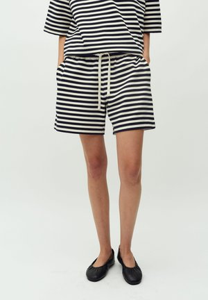 Stribet bomuldsbluse med en afslappet pasform og korte ærmer, parret med matchende shorts med snoretræk. Farver: marineblå og creme. Flade sorte sko.