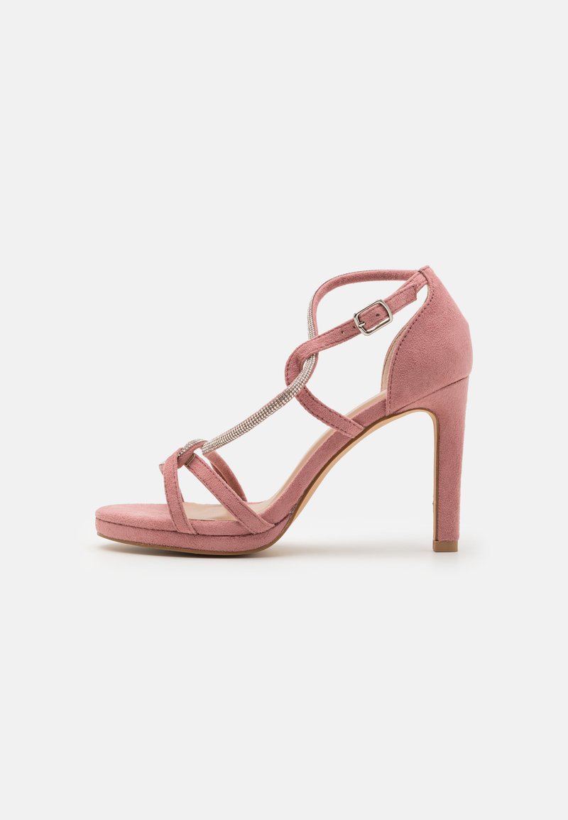 Sandale à talons hauts en daim rose avec un design de lanières croisées, ornée d'un accent en strass et d'une bride de cheville réglable.