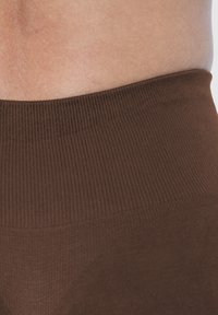 Bruine geribbelde tailleband van leggings, met een gladde textuur en een strakke pasvorm, zonder zichtbare patronen of hardwaredetails.