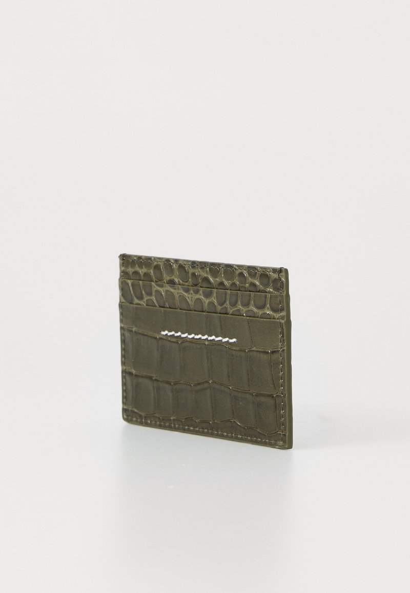 Slim olive green wallet with crocodile texture and white stitching, standing upright on a white surface.