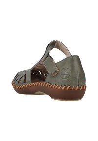 Sandal de piel verde con diseño de cortes, correa ajustable y detalles de costura marrón a lo largo de la suela. Plantilla plana para mayor comodidad.