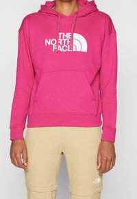 Sudadera con capucha rosa de mezcla de algodón, con un gran logo blanco en el frente, bolsillo delantero y capucha con cordón. Textura lisa.