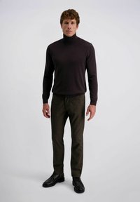 Donkerbruine coltrui gecombineerd met gestructureerde geruite broek in aardetinten, aangevuld met zwarte veterschoenen. Eenvoudig, aansluitend ontwerp.