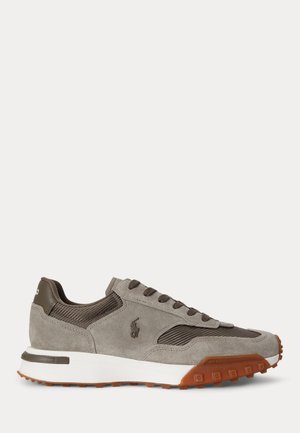 Sneaker basso in camoscio grigio e mesh con suola e lacci marroni, intersuola bianca e logo ricamato sul lato.