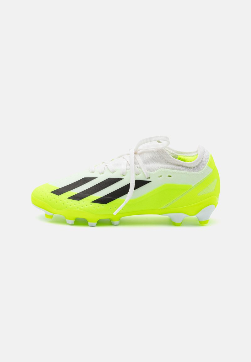 Botín de fútbol de color amarillo neón con franjas negras, cordones blancos y parte superior de malla. Cuenta con superficie texturizada y tacos de goma para un mejor agarre.