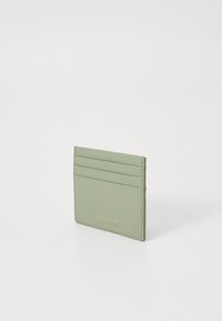 Mint green leather cardholder with four slots, textured surface, and embossed logo in gold on the front. Compact rectangular shape.