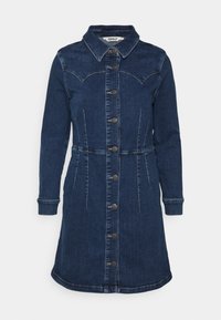 Granatowa sukienka dżinsowa z długimi rękawami, guziki na przodzie, szwy w yoke na klatce piersiowej oraz dopasowanym pasie.