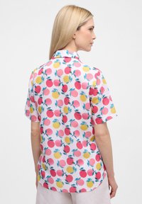 Camicia a maniche corte con uno sfondo rosa e un motivo ripetuto di frutti rossi, gialli e verdi. Tessuto leggero e liscio con colletto.