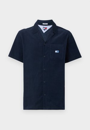 Camisa de botão de manga curta em tecido de veludo-cotele azul-marinho, com um bolso no peito e um patch de logo. Apresenta um colarinho com recorte e uma textura suave.