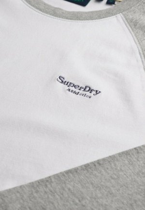 Felpa grigia e bianca con maniche corte e collo rotondo, caratterizzata da un logo ricamato "SuperDry Athletics" in blu scuro sul petto.