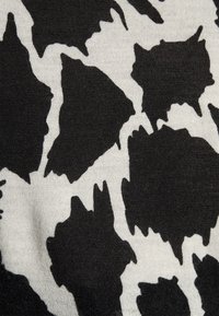 Black and white fabric featuring a bold, abstract pattern with irregular shapes. The texture is soft and smooth, typical of knit materials.