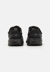 Baskets de sport noires avec dessus en maille et synthétique, col rembourré, sangle Velcro ajustable et semelle en caoutchouc. Logo de la marque sur le talon.