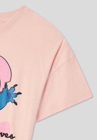 Jasnoróżowa bawełniana koszulka z niebieskim wzorem graficznym i czarnymi akcentami. Krótkie rękawy i okrągły dekolt. Miękka tekstura.