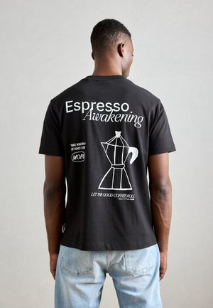 Zwarte katoenen t-shirt met witte tekst en een afbeelding van een koffiezetapparaat. Met korte mouwen en een relaxed-fit.